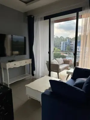 a living room with a tv and a couch and a table at Palmyrah Surin sea view in Surin Beach