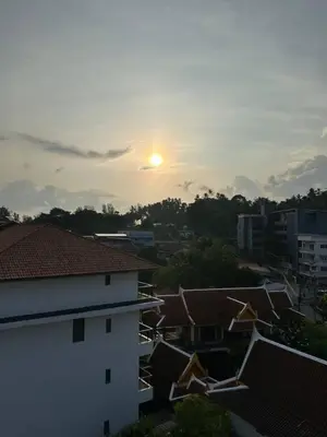 a sunset over a city with roofs and buildings at Palmyrah Surin sea view in Surin Beach