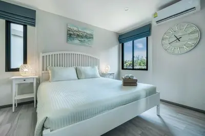 a bedroom with a bed with a large clock on the wall at Studio Apartment by the Sea E413 in Phuket Town