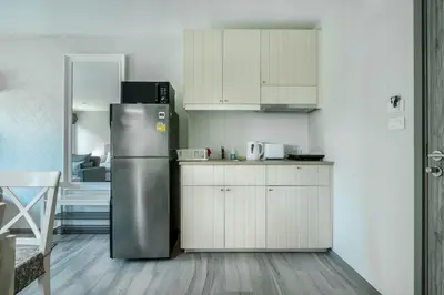 a kitchen with a stainless steel refrigerator and white cabinets at Studio Apartment by the Sea E413 in Phuket Town
