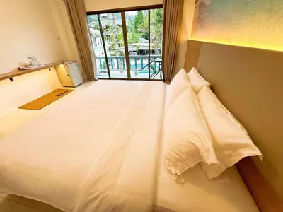 a bedroom with a large white bed with a window at The coconut nanai resort in Patong Beach
