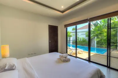 a bedroom with a large bed and a pool at Tropical 3BR Pool Villa Nga Chang NC10, Gated Residence, 10 min Drive to Nai Harn Beach in Rawai Beach