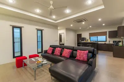 a living room with a black leather couch and red pillows at Tropical 3BR Pool Villa Nga Chang NC10, Gated Residence, 10 min Drive to Nai Harn Beach in Rawai Beach