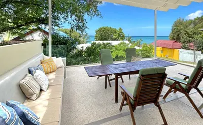 a patio with a table and chairs and the ocean at At the Beach Spacious 2-level Design Home for 2-5 and 1 infant, Ao Yon Beach Phuket in Ban Ao Makham