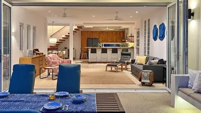 a living room with blue chairs and a kitchen at At the Beach Spacious 2-level Design Home for 2-5 and 1 infant, Ao Yon Beach Phuket in Ban Ao Makham