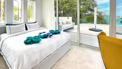 a bedroom with a large bed with blue bows on it at At the Beach Spacious 2-level Design Home for 2-5 and 1 infant, Ao Yon Beach Phuket in Ban Ao Makham