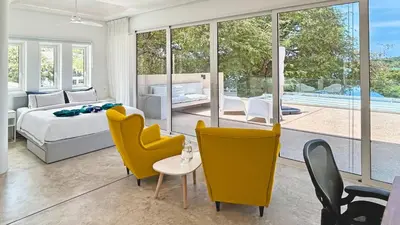 a bedroom with yellow chairs and a bed and a table at At the Beach Spacious 2-level Design Home for 2-5 and 1 infant, Ao Yon Beach Phuket in Ban Ao Makham