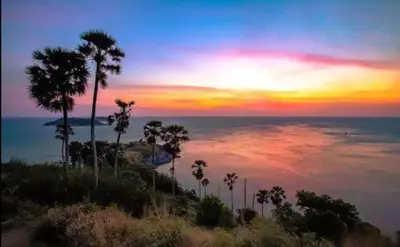 a sunset over the ocean with palm trees on a hill at Andaman homestay villa at rawai in Ban Saiyuan (1)