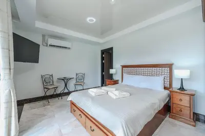 a bedroom with a large bed and a tv at Уютные апартаменты NBC Nai Harn in Rawai Beach