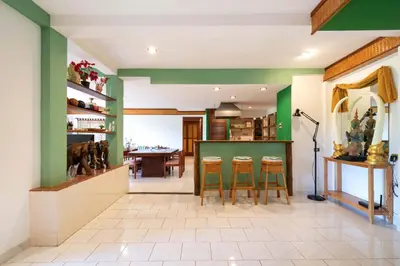 a kitchen with green walls and a table with stools at Unique Style 3BR Apartment BGV 216 in Gated Residence, Kata in Kata Beach