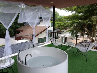 a bath tub sitting on top of a patio with chairs at Nariya Bayfront Phuket in Chalong