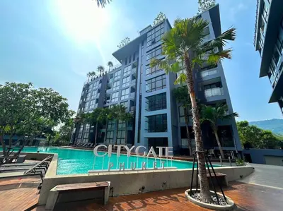 a building with a palm tree next to a swimming pool at Nicest Condo in City gate Kamala 6km Patong #c118 in Kamala Beach