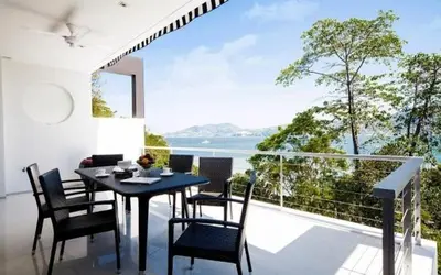 a dining room with a table and chairs on a balcony at Atika Villas in Patong Beach