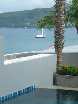 a boat in the water with a palm tree at Atika Villas in Patong Beach