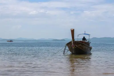 a man is sitting on a boat in the water at JK Studio, Koh Yao Noi in Ko Yao Noi