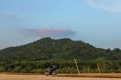 a person riding a motorcycle in front of a mountain at JK Studio, Koh Yao Noi in Ko Yao Noi