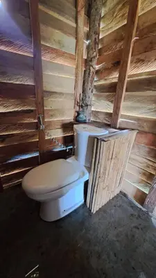 a bathroom with a toilet in a wooden wall at Big Hug Home - Sa med kaw in Ban Takhrai