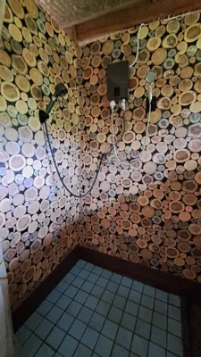 a bathroom with a wall covered in wooden logs at Big Hug Home - Sa med kaw in Ban Takhrai