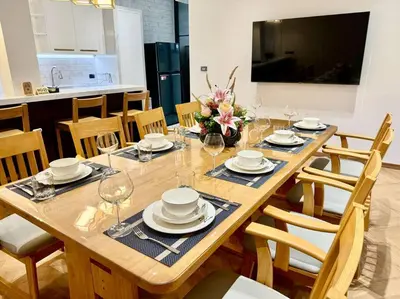 a wooden table with plates and wine glasses on it at Naka Central Happy Home in Phuket city in Ban Rangeng