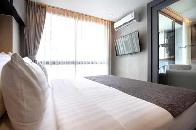 a bedroom with a large white bed with a window at Urban Suite CTG B702 in a Gated Tropics Kamala Residence with 3 Pools & Gym in Kamala Beach