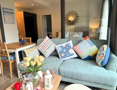 a living room with a blue couch with colorful pillows at Deck Condo private apartment by Lofty in Patong Beach