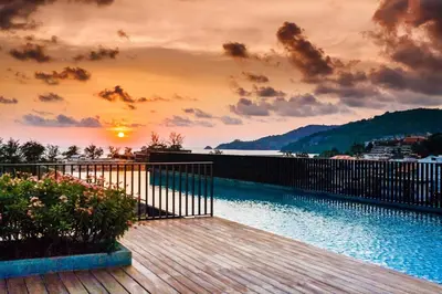 a wooden deck with a sunset in the background at Deck Condo private apartment by Lofty in Patong Beach