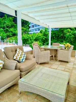 a patio with wicker chairs and a table and an umbrella at Eagles Nest Patong in Patong Beach