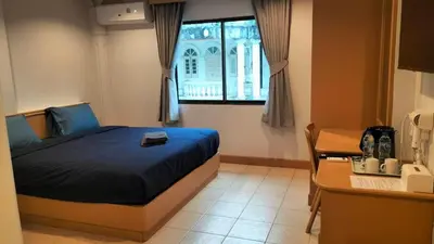 a bedroom with a bed and a desk and a window at JB House Patong in Patong Beach