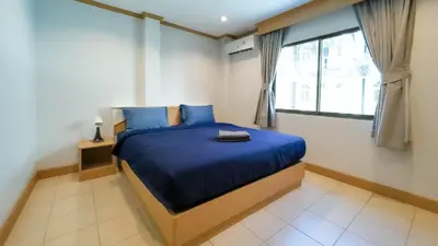 a bedroom with a bed with blue sheets and a window at JB House Patong in Patong Beach