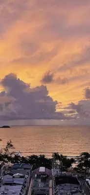 a sunset over the water with buildings and the ocean at Patong Tower Dream Sea View Apartment in Patong Beach