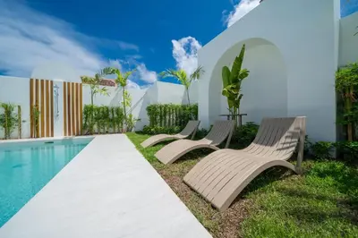 a group of chairs sitting next to a swimming pool at Brand New 4BR Balinese Style Pool Villa Kaia just 5 min drive from NaiHarn Beach in Rawai Beach