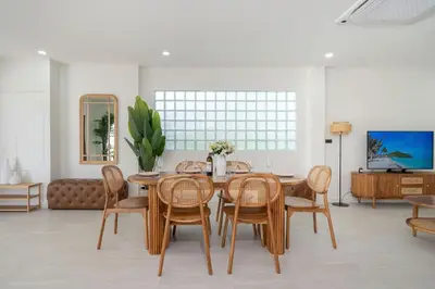 a dining room with a wooden table and chairs at Brand New 4BR Balinese Style Pool Villa Kaia just 5 min drive from NaiHarn Beach in Rawai Beach