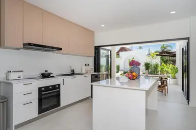 a kitchen with white cabinets and a counter top at Brand New 4BR Balinese Style Pool Villa Kaia just 5 min drive from NaiHarn Beach in Rawai Beach