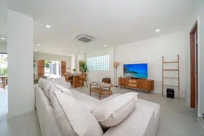 a living room with a white couch and a table at Brand New 4BR Balinese Style Pool Villa Kaia just 5 min drive from NaiHarn Beach in Rawai Beach