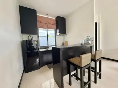 a kitchen with black cabinets and a table and chairs at Garden 2 bedrooms pool villa in Laguna Phuket