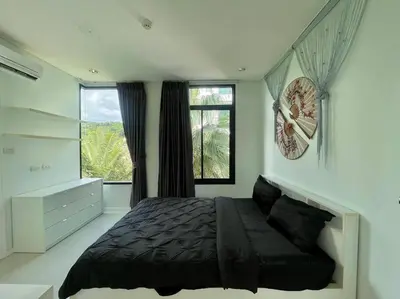 a bedroom with a black bed and a window at Kamala Regent Condo in Kamala Beach
