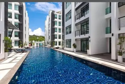 a swimming pool in the middle of two buildings at Kamala Regent Condo in Kamala Beach