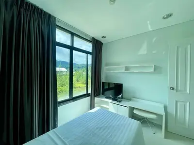 a bedroom with a bed and a desk and a window at Kamala Regent Condo in Kamala Beach