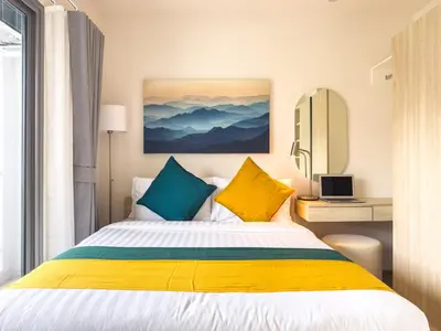 a bedroom with a bed with yellow and blue pillows at PHYLL Condo Private Beach Vibes at Central Phuket 1 BR Unique Garden View in Ban Rangeng