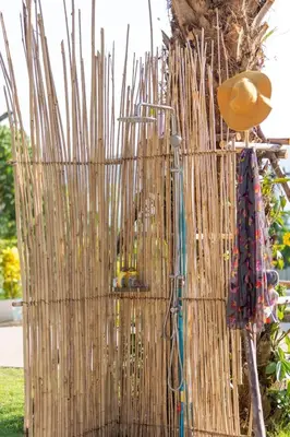 a fence with umbrellas and a hat next to a tree at Sirinary Villa Phuket in Ban Ao Makham