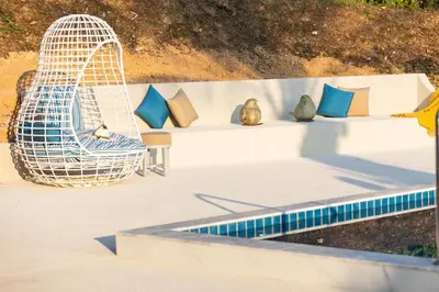 a bench with pillows and a chair next to a pool at Sirinary Villa Phuket in Ban Ao Makham