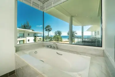 a large white bath tub in a room with a large window at Karon Beachfront Apartment 724 in Karon Beach