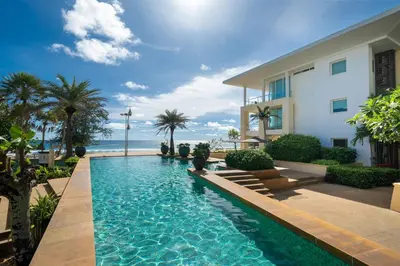 a swimming pool in front of a house with the ocean at Karon Beachfront Apartment 724 in Karon Beach