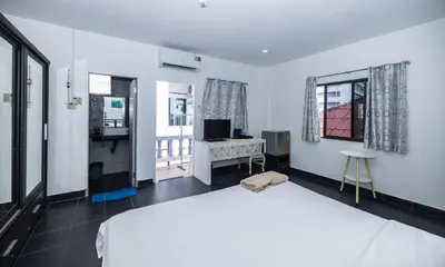 a bedroom with a white bed and a desk at Belle Cose Guest House Phuket in Patong Beach