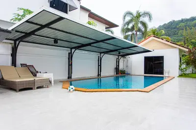 a swimming pool in a house with awning at Chalong V pool villa in Ban Klang