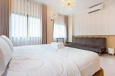 a bedroom with a large white bed and a couch at Chalong V pool villa in Ban Klang
