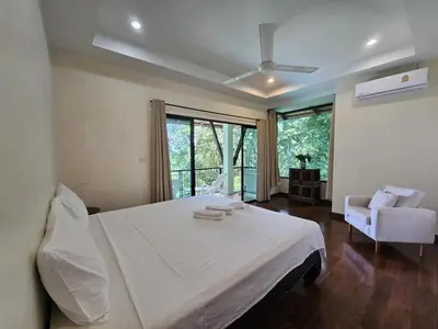 a bedroom with a large white bed and a chair at Beachfront villa in Rawai in Phuket Town