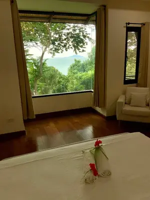 a bedroom with a bed and a large window at Beachfront villa in Rawai in Phuket Town