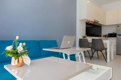 a living room with a couch and a laptop on a table at Spacious Pool View 1BR Apartment in Utopia Naiharn Residence near Beach, UTN D604 in Rawai Beach