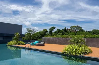 a swimming pool with a bench and chairs next to a building at Spacious Pool View 1BR Apartment in Utopia Naiharn Residence near Beach, UTN D604 in Rawai Beach